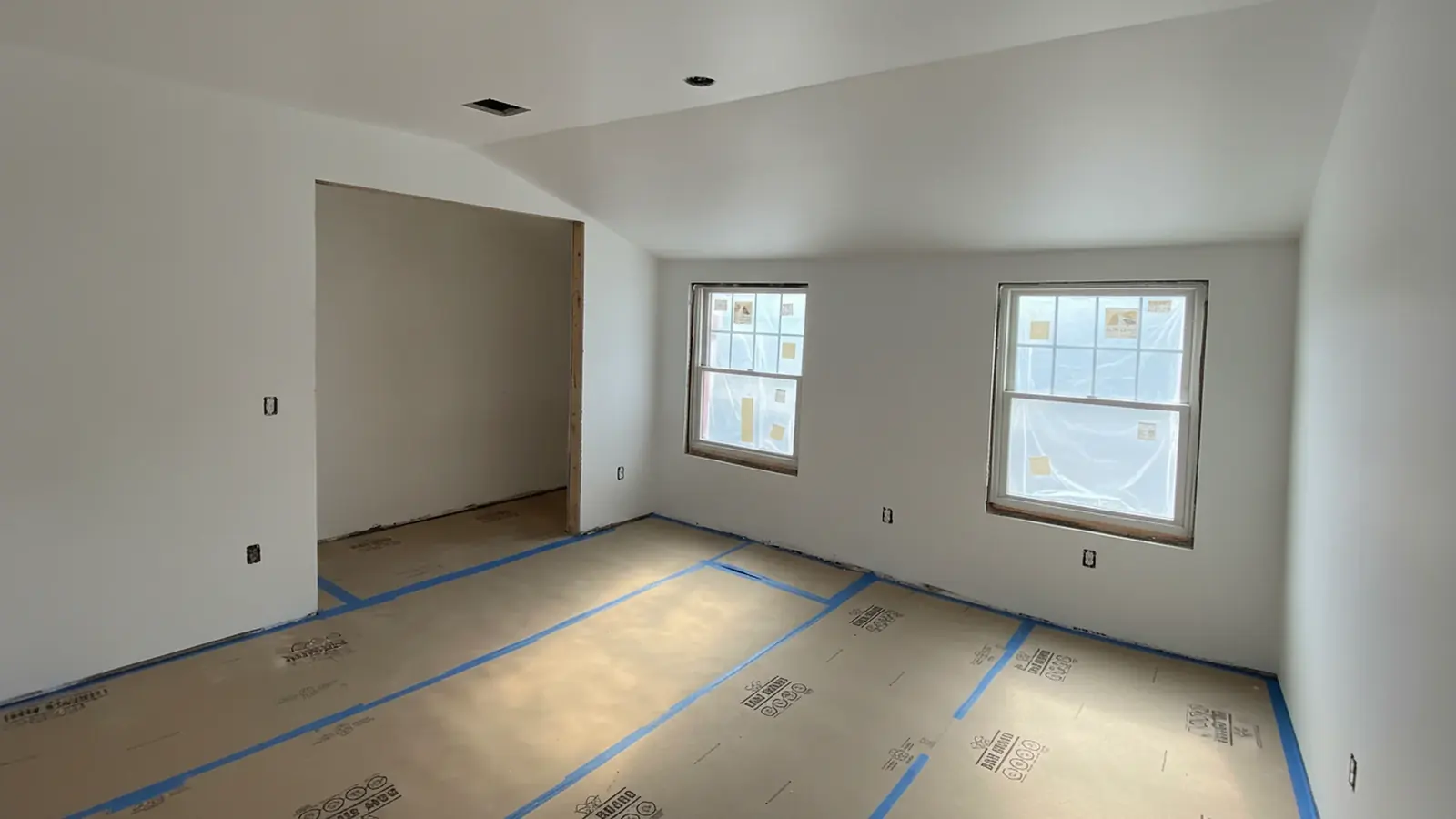 Bedroom being painted with the floor covered by protective paper and plastic