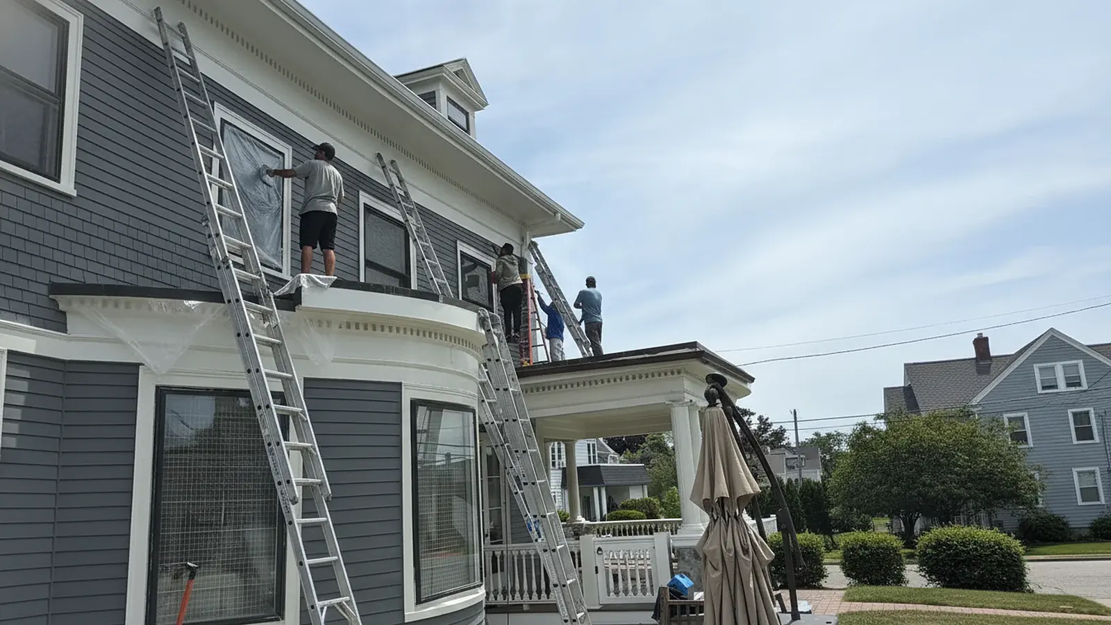Painter on a ladder working on exterior trim of a house