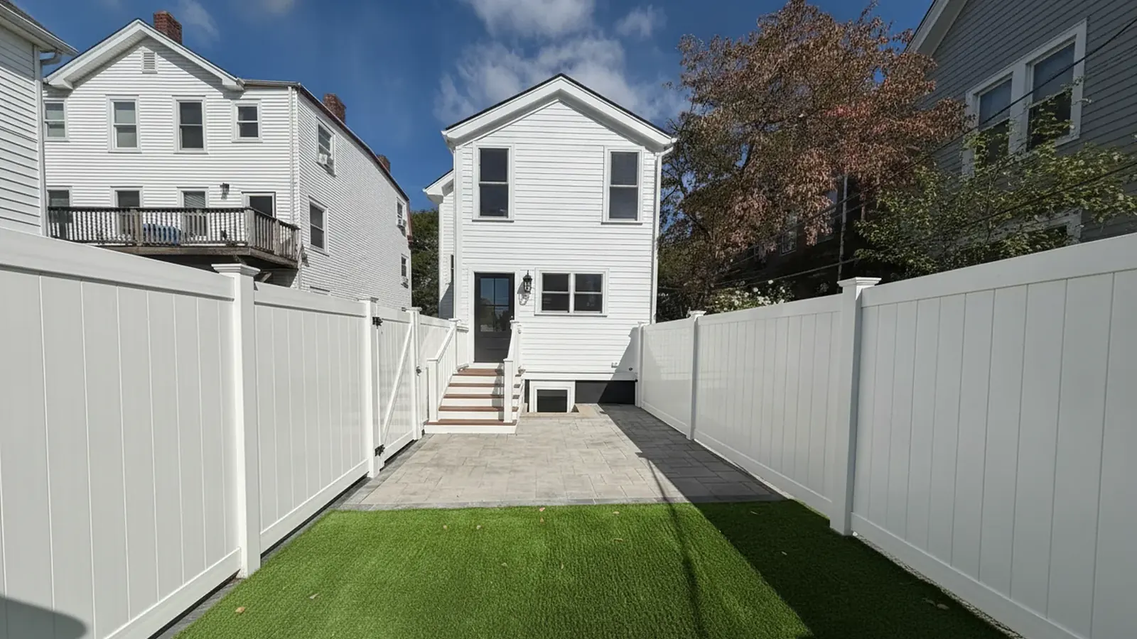 Large white Colonial house with freshly painted siding seen from the backyard