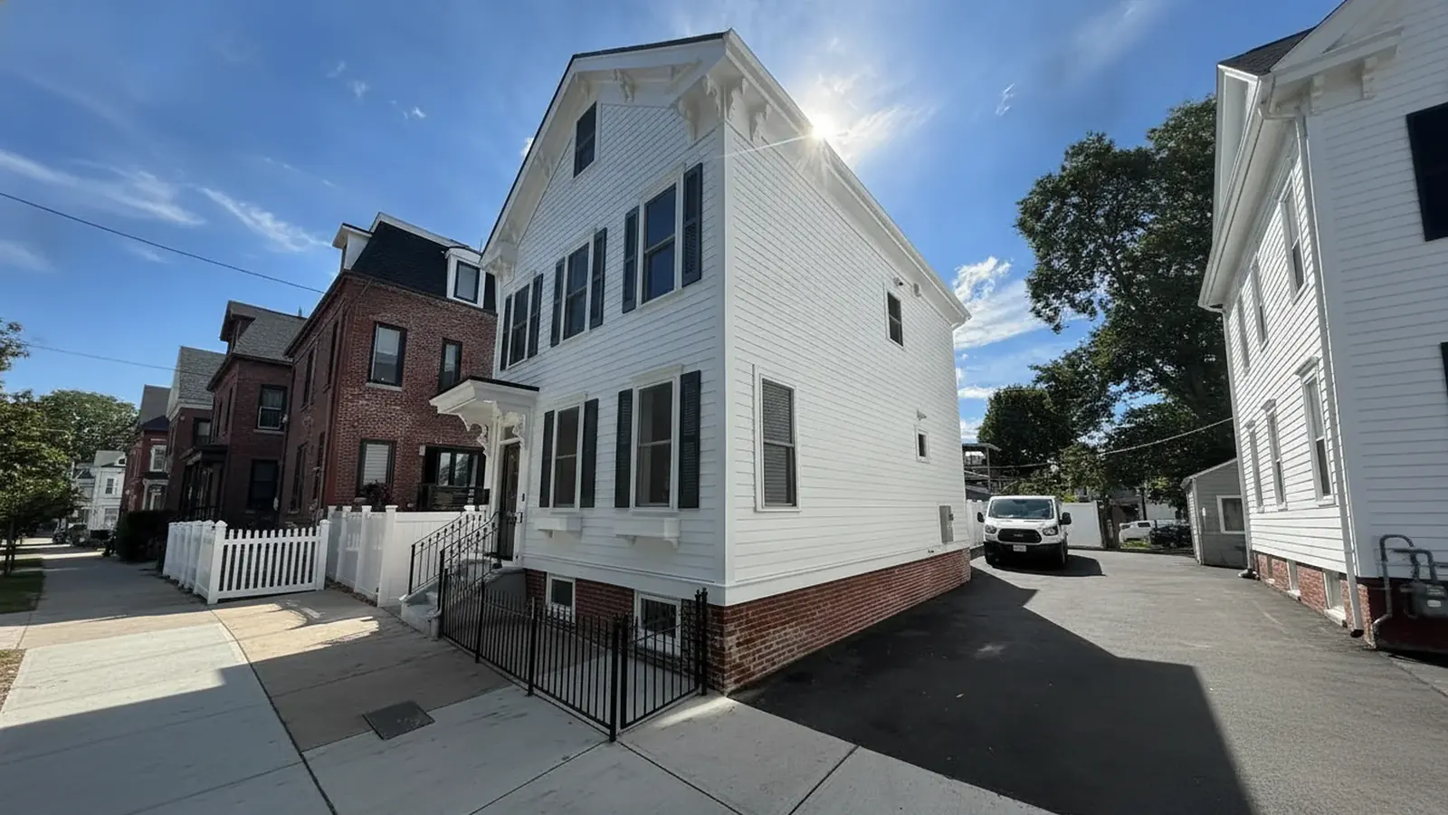 White colonial house exterior with black shutters after painting
